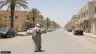 شارع في أسوان وقت الظهيرة تحت شمس قوية وظلال قصيرة لسيارات متوقفة